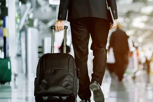 Man walking in an airport with a suitcase